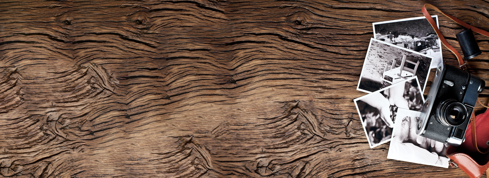 Vintage camera and black and white family photos on rustic wood table for convert to digital media by DVD Your Memories San Diego.