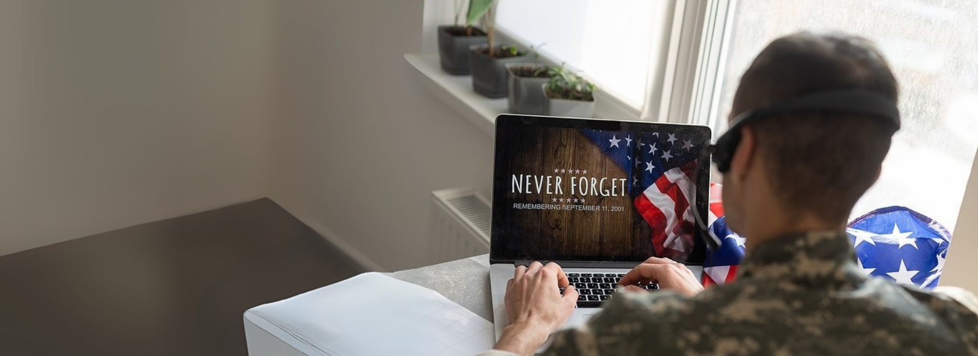 Military veteran editing video on laptop with American flag, representing custom video editing by DVD Your Memories San Diego.