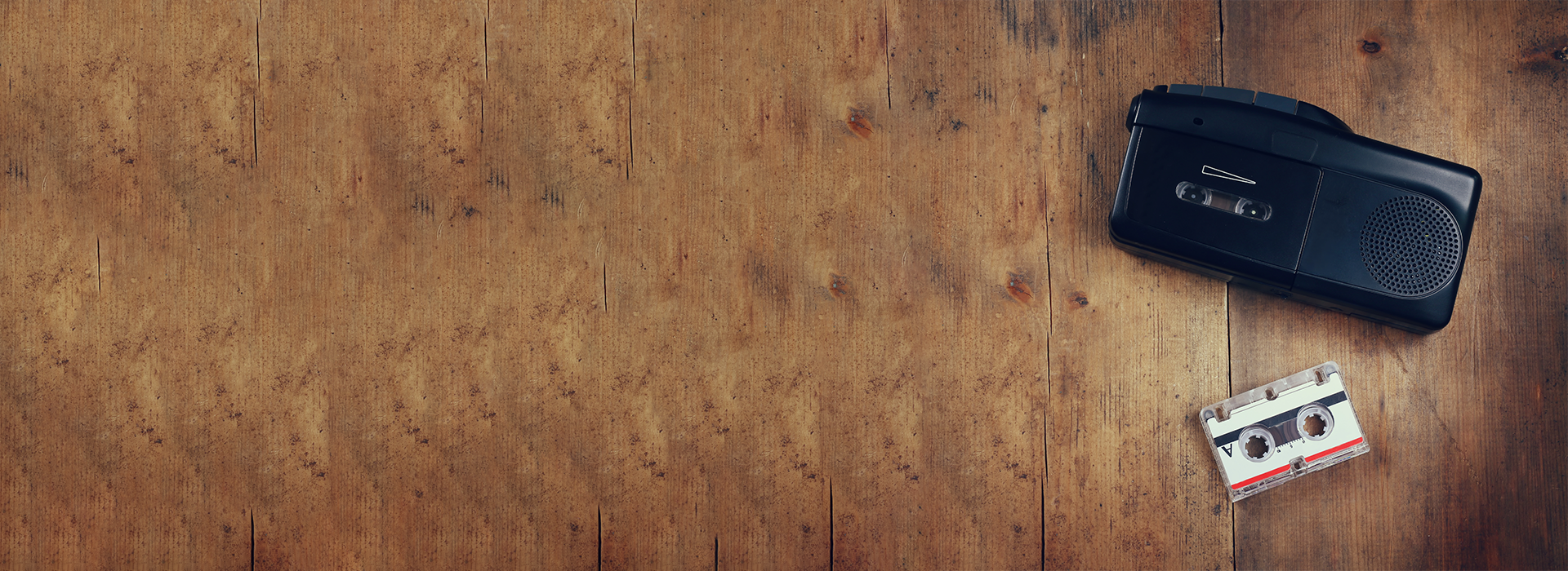 Vintage cassette recorder and tape on wooden surface representing photo, video, audio services by DVD Your Memories Orange County.