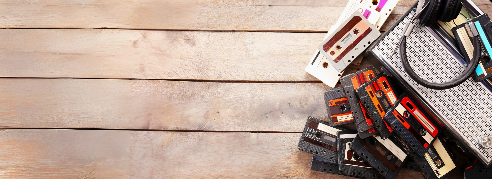 Vintage cassette tapes and film reels on wooden table representing photo, video, audio services by DVD Your Memories South Bay.