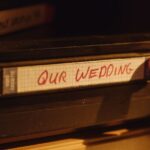 Someone pushes a VHS tape labeled "Our Wedding" into a player.