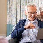 A happy older couple looks at their transferred files on a tablet.