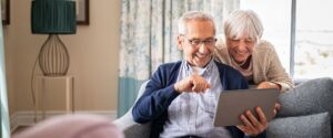 A happy older couple looks at their transferred files on a tablet.