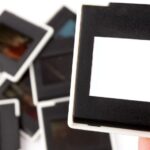 Hand holding a blank film slide above a pile of 35 mm slides