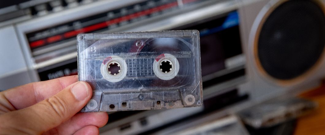 Hand holding an audio cassette, about to play the tape in a boombox