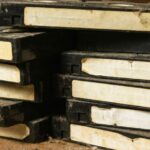A stack of old VHS tapes with visible dirt and degradation on the labels.