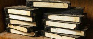 A stack of old VHS tapes with visible dirt and degradation on the labels.
