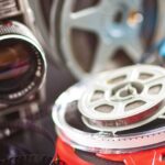 A stack of Super 8 next to a film camera.