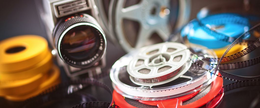A stack of Super 8 next to a film camera.