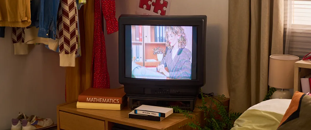 An old box tv is playing a VHS tape and it looks very grainy and blown out.